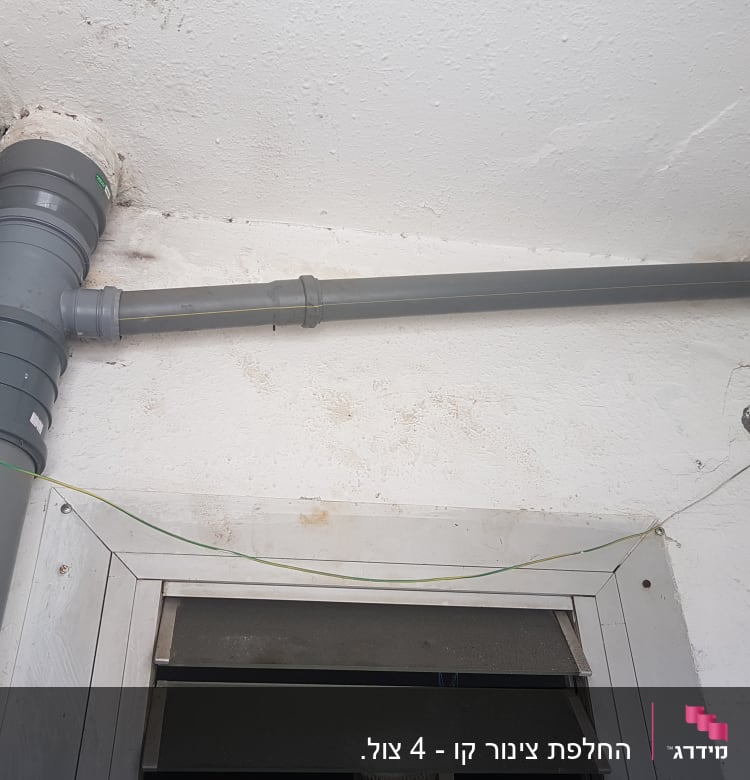 צינור פלסטיק אפור מותקן על קיר לבן